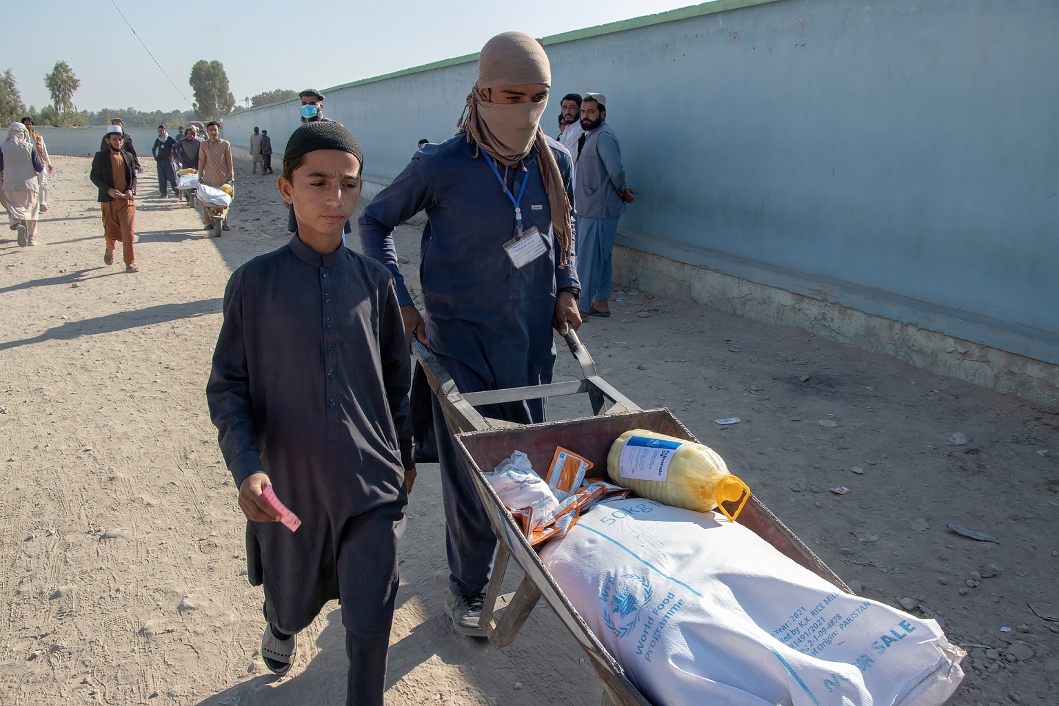Två afghanska ungdomar och skottkärra lastad med mathjälp.