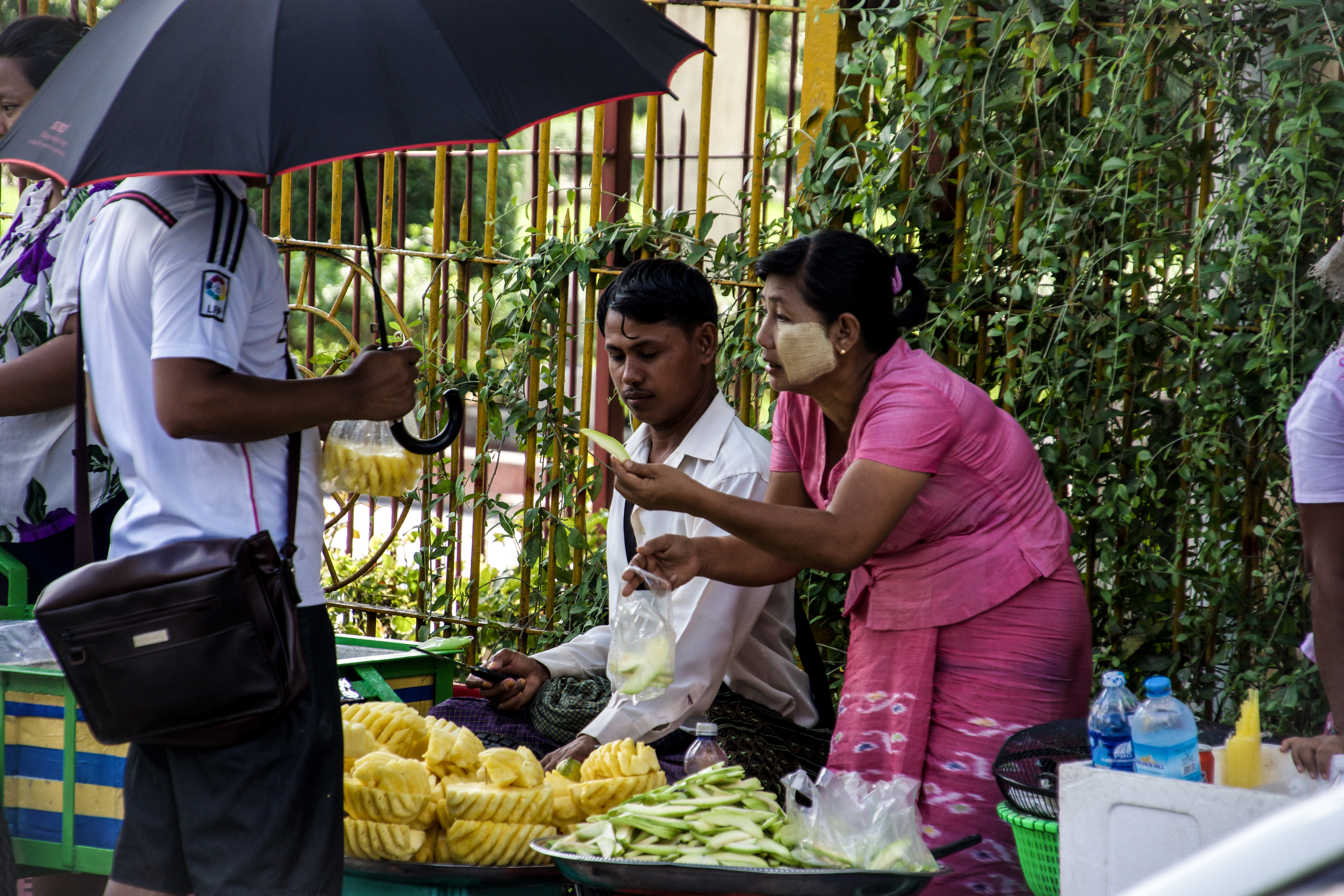 Nainen ja mies myyvät hedelmiä kadunvarrella ostajalle.