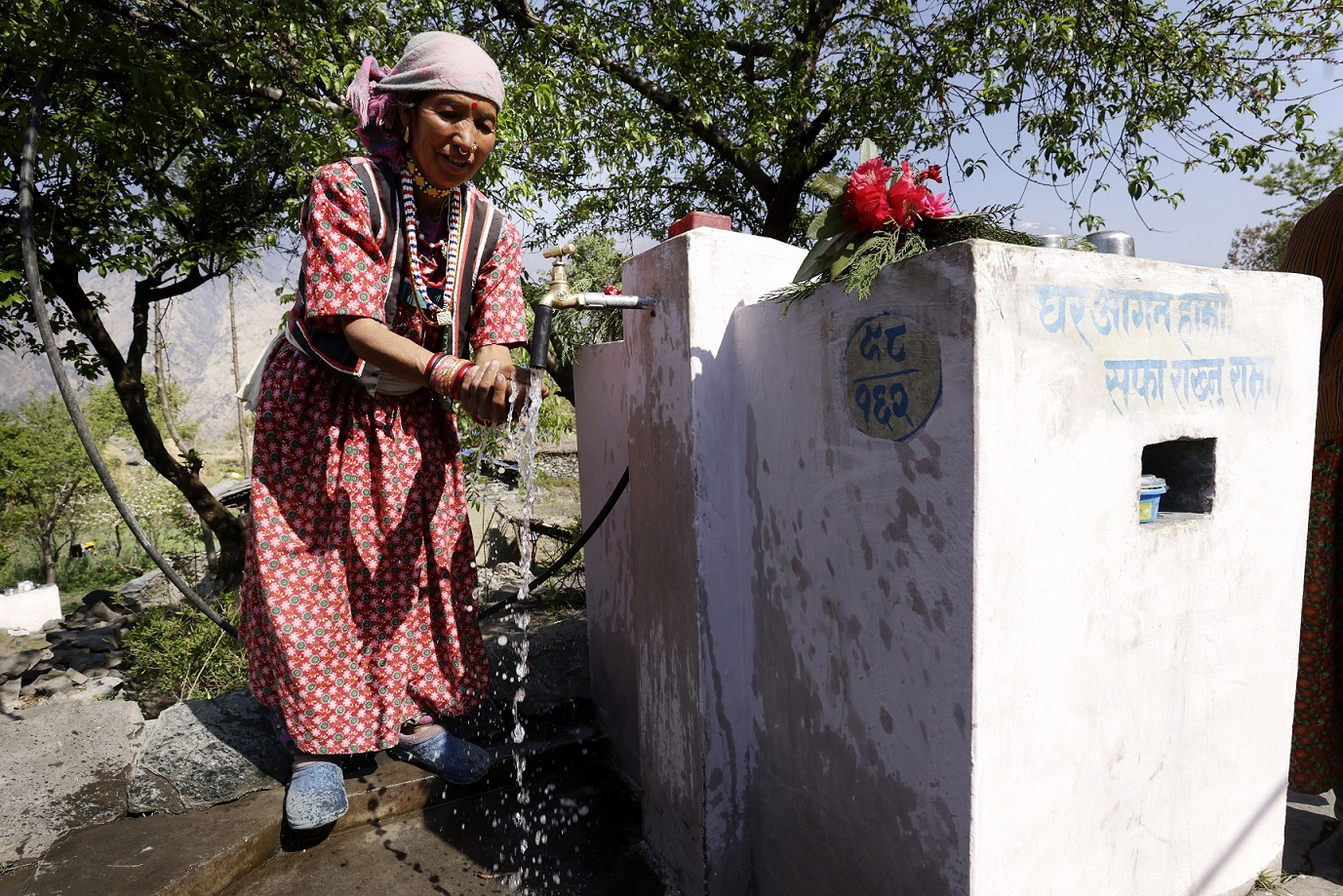 Sanja Thekare washes her hands at an outdoor water tap.