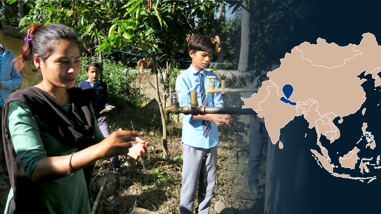 Nepalilaisia koululaisia pesemässä käsiään koulun vesipisteellä. Kuvassa myös Aasian kartta, johon Nepal on merkitty.