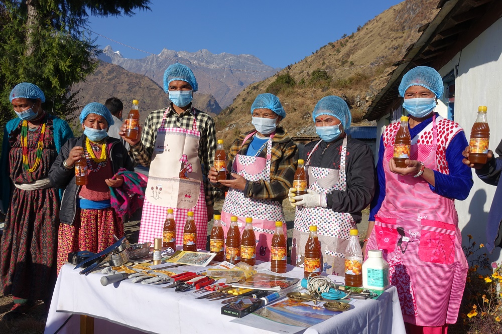 Six cooperative members stand behind a sales table. They all have sea buckthorn juice bottles in their hands.