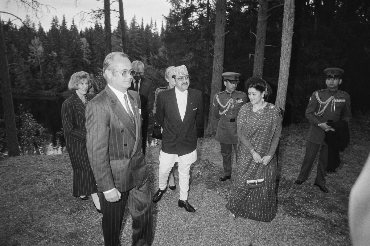 Nepalese royal couple along with adjutants and Oulu city council chairman and three more Finnish people walking in forest. Photo is black and white, from 1989.