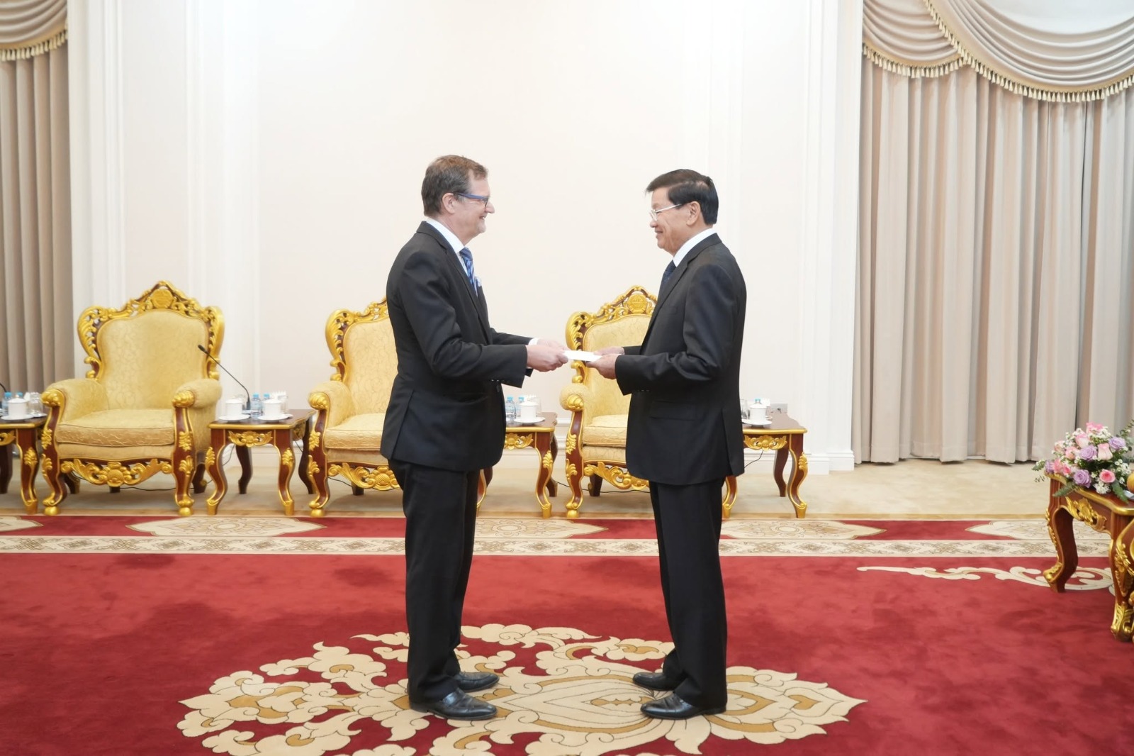 two men handling a document, with Ambassador of Finland Pekka Voutilainen on the left, giving away a document to the President of Lao People's Democratic Republic, Thongloun Sisoulith