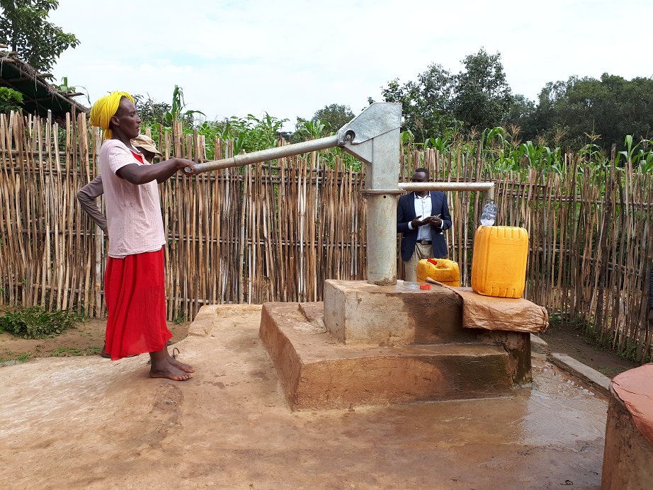 Woman pumping water from a well