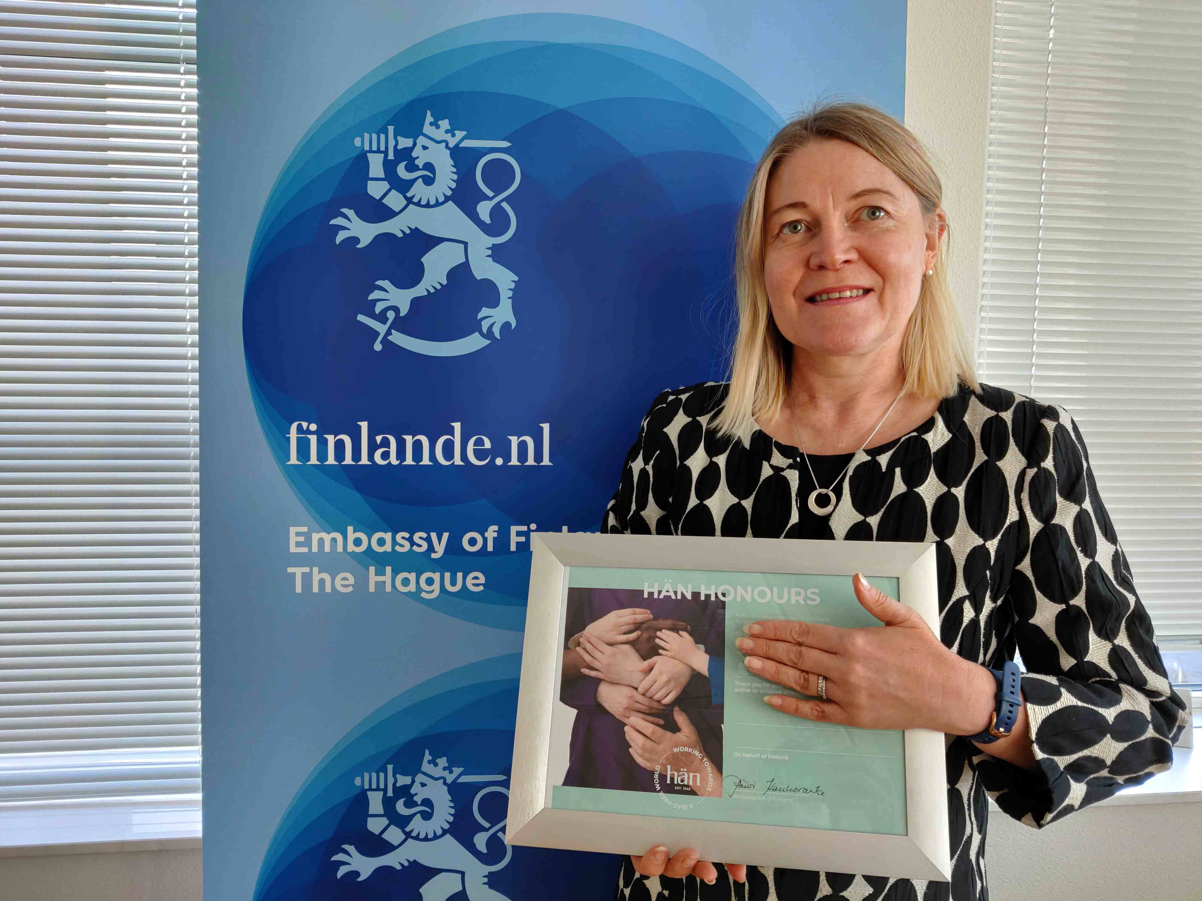 Ambassador Päivi Kaukoranta with the recognition and a roll up of the Embassy of Finland in the Hague