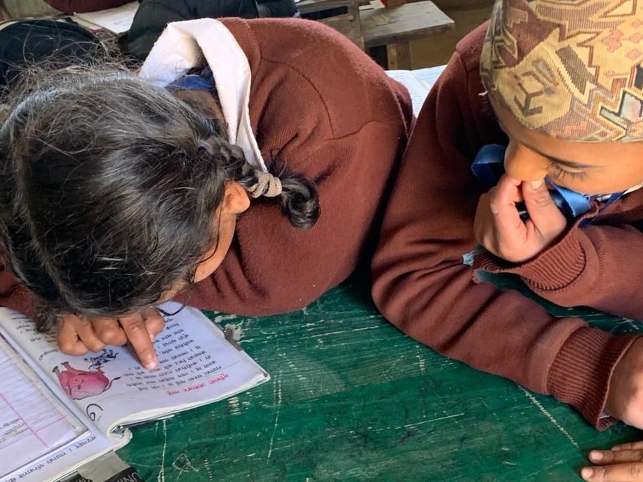 Kaksi lasta lukemassa koulukirjaa.
