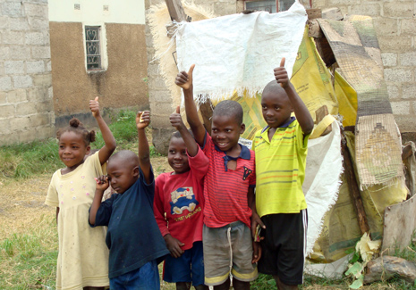 Barn i det inofficiella bostadsområdet i Madimba. I bakgrunden den latringrop som används nu för tiden. Foto: Huussi rf