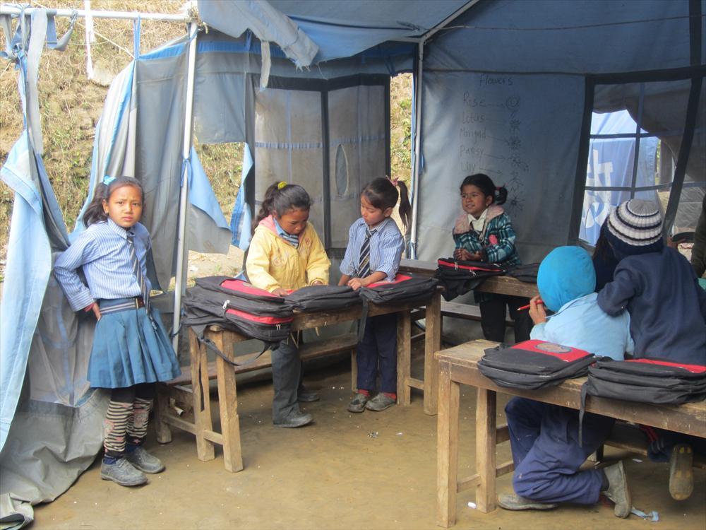 Koululaisia repaleisessa luokkahuoneessa odottamassa opetuksen alkamista.