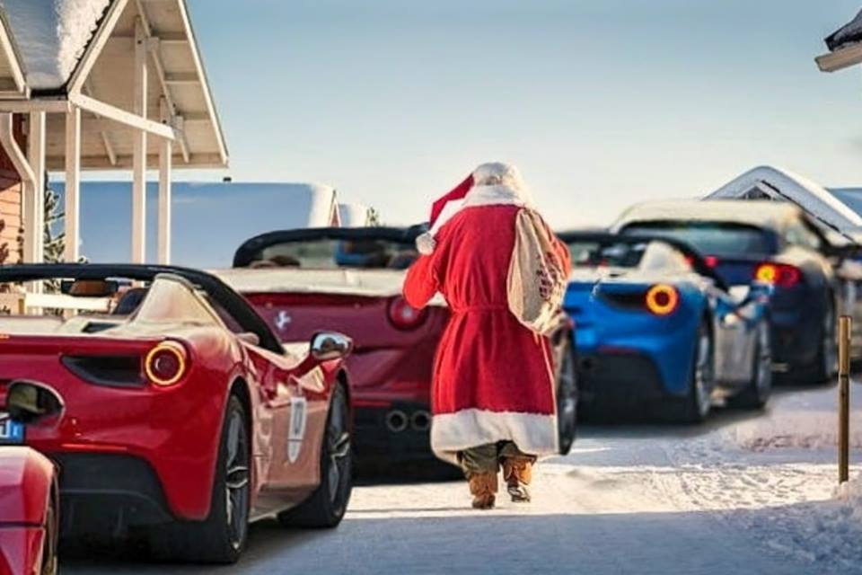 Joulupukki kävelee Ferrari-autojen vierellä.