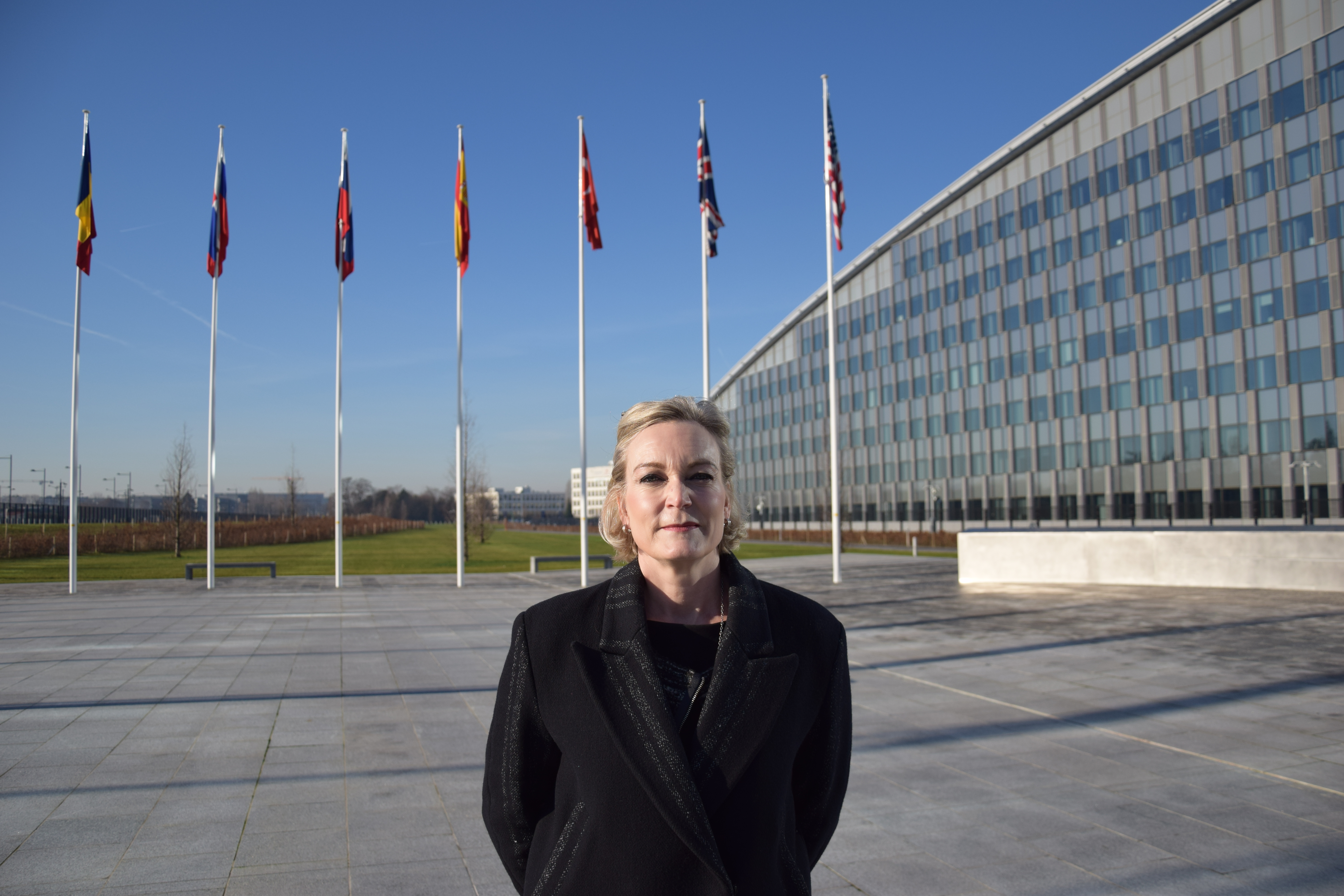 Piritta Asunmaa seisoo Naton päämajan lippupihalla. 