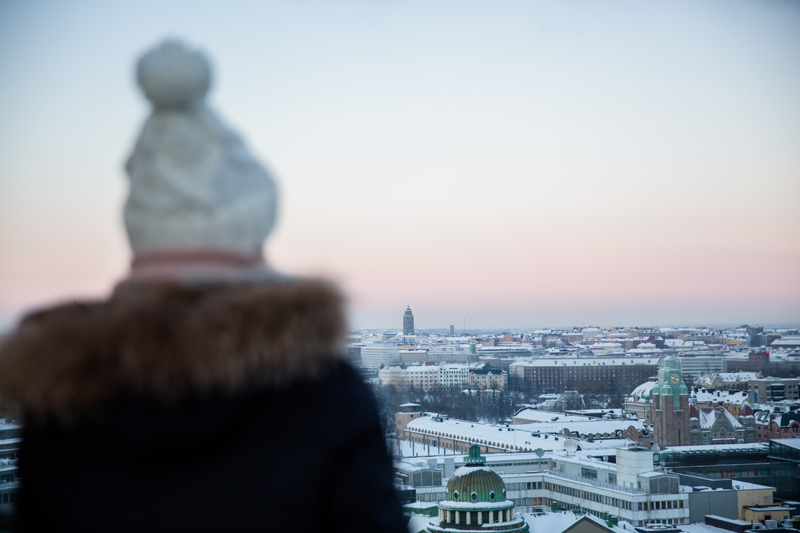 Nainen katsoo lumista maisemaa Helsingin keskustassa.