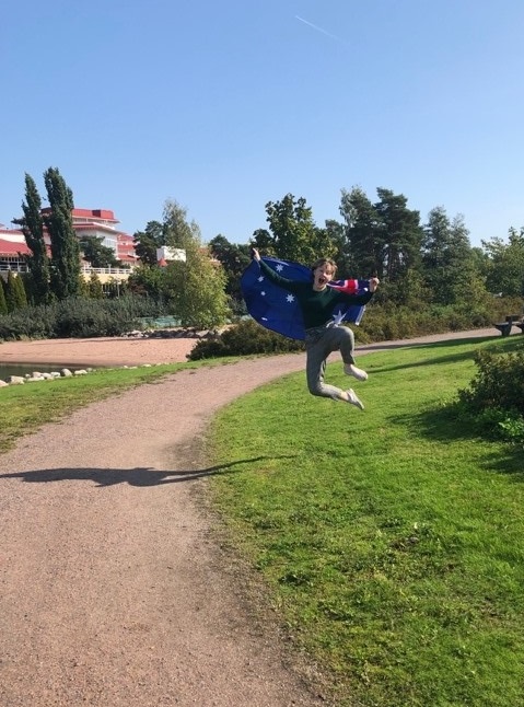 Abigail Barrett jumping up while holding an Australian flag in Naantali, Finland.