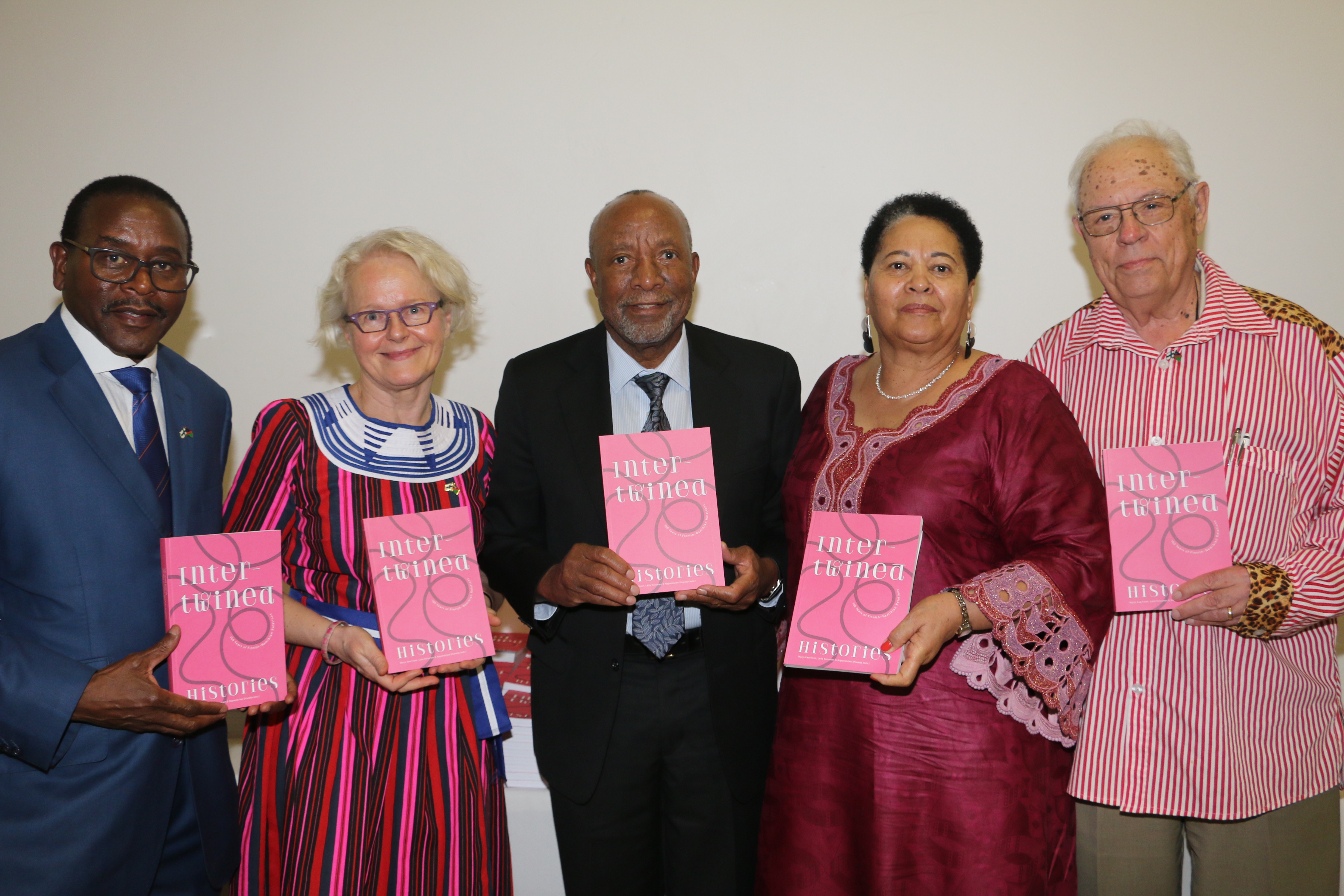 Kuvassa suurlähettiläs Pirkko-Liisa Kyöstilä, Namibian varapresidentti Nangolo Mbumba ja muita arvovieraita käsissään Intertwined Histories -teokset.