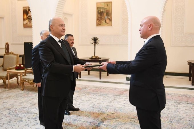 Suomen suurlähettiläs ojentaa valtuuskirjaa Irakin presidentille hienossa salissa.
